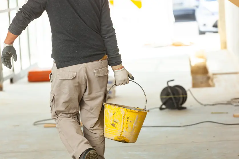 Construction worker with cement mortar on construction site.