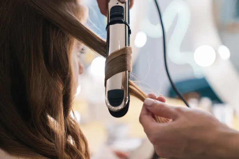 Close up of a hairdresser curling up customers hair in the beauty salon