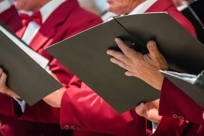 Close up of mens choir members holding singing book while performing in a cathedral in Rochester, Kent, UK