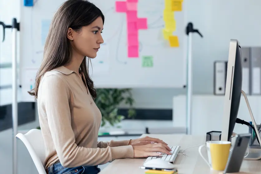 Shot of beautiful young business woman working with computer while sitting in desk in modern startup office.