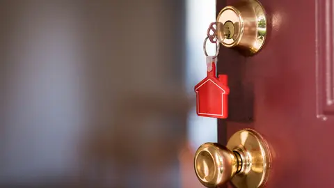 House key with house shape keychain in the door