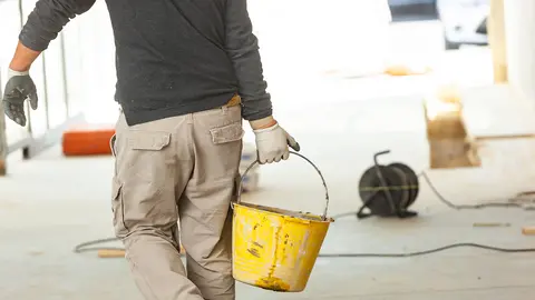 Construction worker with cement mortar on construction site.