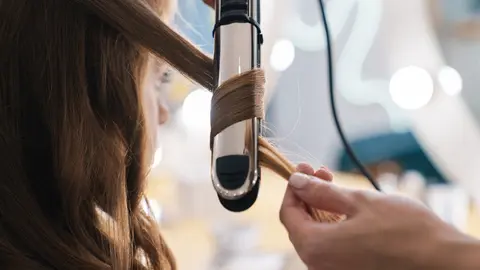 Close up of a hairdresser curling up customers hair in the beauty salon