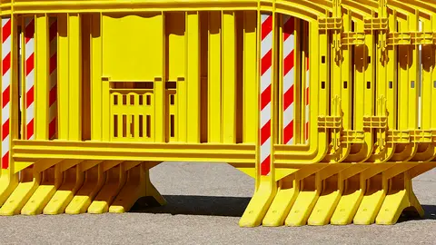 Yellow plastic barrier fence over an asphalt road. Security