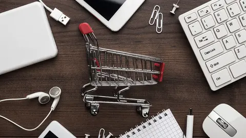 shopping online concept. small red trolley and gadgets on the table