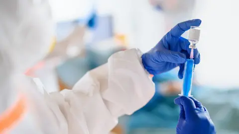 Unrecognizable doctor holding vaccine in hospital, coronavirus concept.