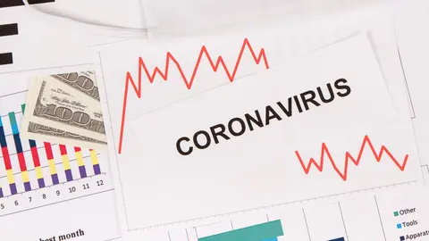 Inscription coronavirus, currencies dollars and downward graphs representing financial crisis caused by Covid-19. Risk of global recession around world