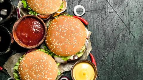 Fast food. Fresh burgers with cola. On a rustic background.