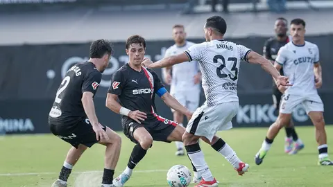 Anuar golpea el balón ante dos jugadores del Sporting